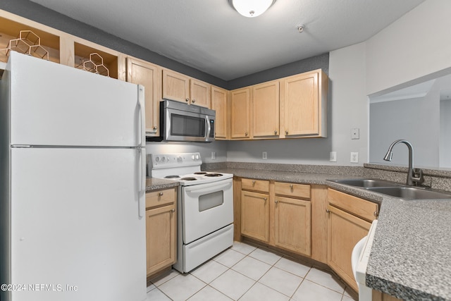 kitchen featuring light brown cabinetry, white appliances, dark countertops, and a sink