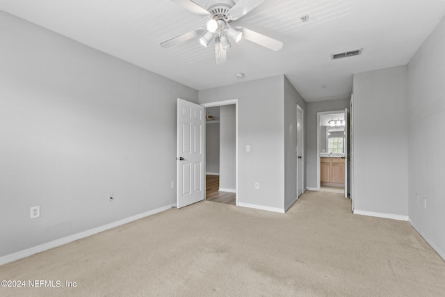 unfurnished bedroom with light colored carpet, ceiling fan, and ensuite bath