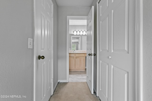 hallway with a sink and light colored carpet