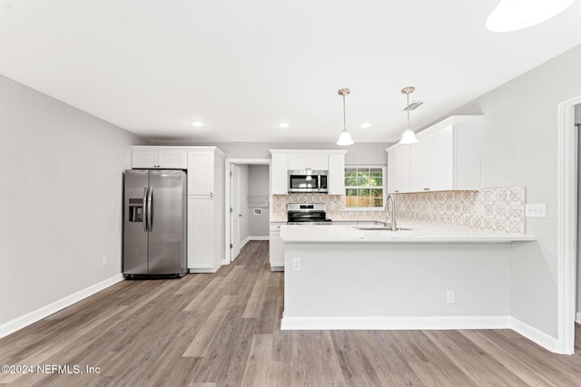 kitchen with stainless steel appliances, white cabinetry, hanging light fixtures, sink, and light hardwood / wood-style flooring