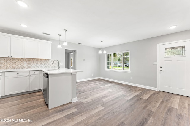 kitchen featuring white cabinets, light hardwood / wood-style floors, sink, and decorative light fixtures