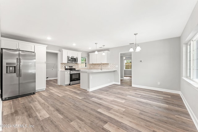 kitchen with stainless steel appliances, light wood-type flooring, hanging light fixtures, white cabinets, and kitchen peninsula