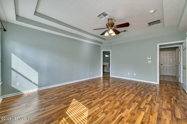 empty room with dark hardwood / wood-style floors, a raised ceiling, and ceiling fan