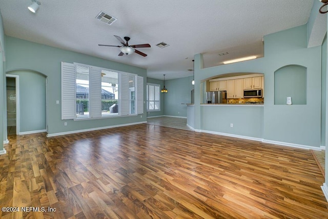 unfurnished living room featuring a textured ceiling, ceiling fan, and hardwood / wood-style floors