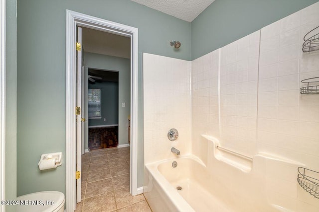 bathroom with toilet, tub / shower combination, a textured ceiling, and tile patterned flooring