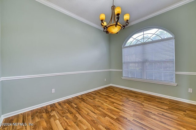 spare room featuring a chandelier, ornamental molding, and hardwood / wood-style floors