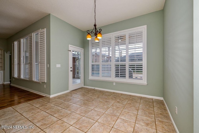 unfurnished room with light tile patterned floors, a chandelier, and a textured ceiling