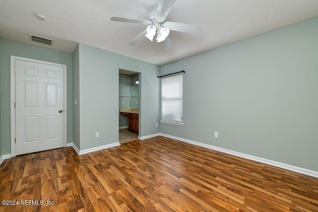 unfurnished bedroom with ceiling fan, a textured ceiling, ensuite bathroom, and dark hardwood / wood-style floors