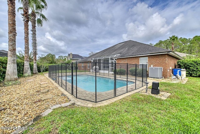 view of swimming pool featuring a lawn, central AC, and a lanai