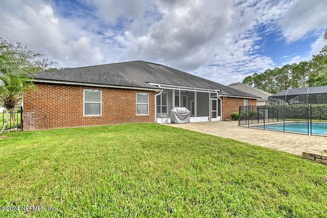 rear view of property featuring a fenced in pool, a sunroom, a lawn, and a patio