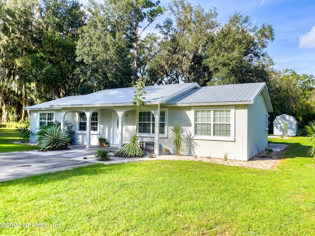 single story home featuring a shed, a front yard, and covered porch