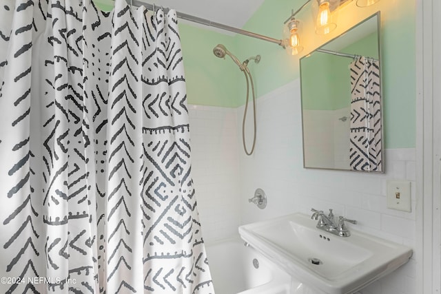 bathroom with shower / bath combo, tile walls, and sink