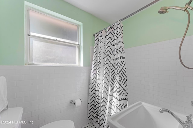 bathroom with toilet, a shower with curtain, tile walls, and sink