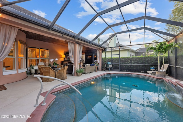 view of pool featuring pool water feature, glass enclosure, a patio area, and grilling area