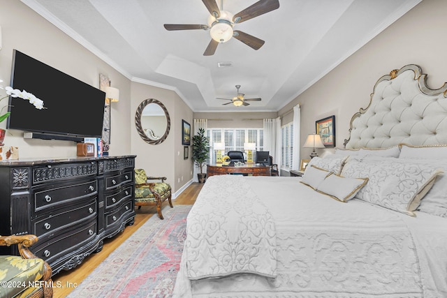 bedroom with a tray ceiling, ceiling fan, wood-type flooring, and ornamental molding