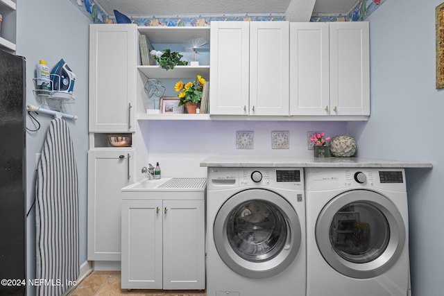 laundry area with sink, cabinets, a textured ceiling, and independent washer and dryer