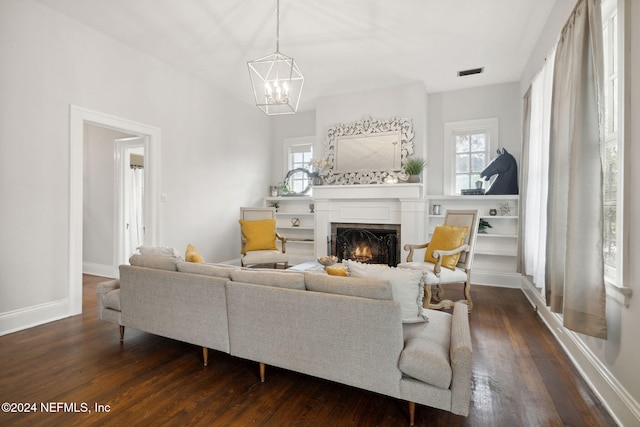 living room with a fireplace, a chandelier, dark hardwood / wood-style floors, and plenty of natural light