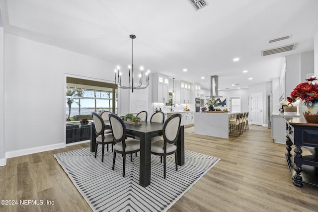 dining area featuring light hardwood / wood-style floors, an inviting chandelier, and sink