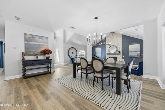 dining area with light hardwood / wood-style floors, vaulted ceiling, and a notable chandelier