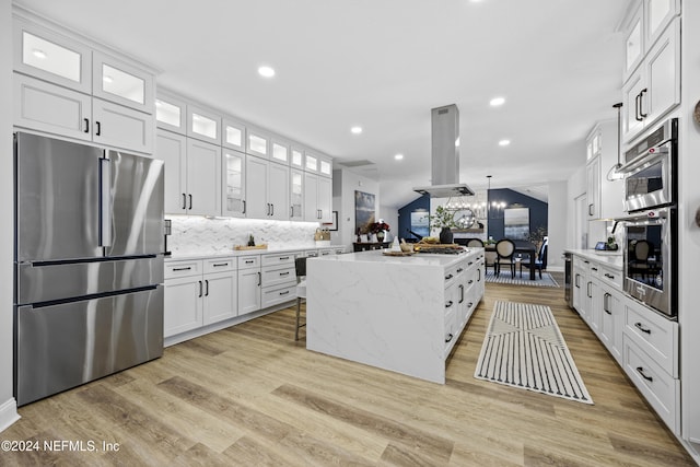 kitchen featuring light hardwood / wood-style flooring, stainless steel appliances, white cabinetry, and island range hood