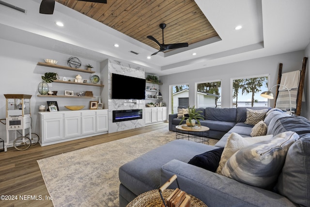 living room featuring ceiling fan, a raised ceiling, wood ceiling, and dark wood-type flooring