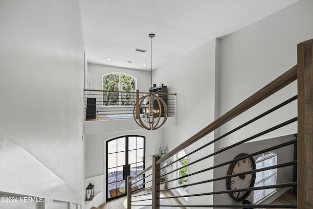 stairs with a chandelier and a textured ceiling