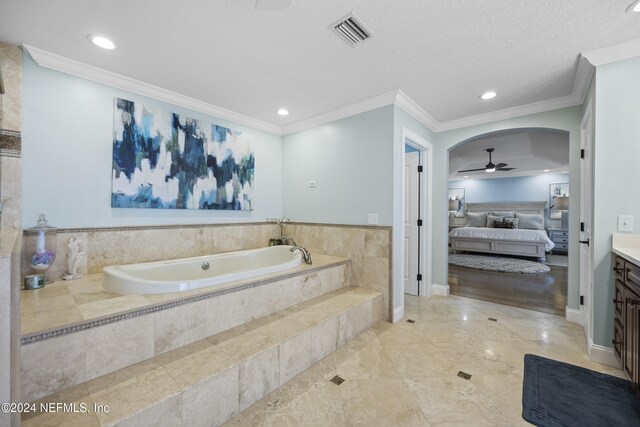 bathroom featuring vanity, ceiling fan, ornamental molding, a textured ceiling, and tiled tub