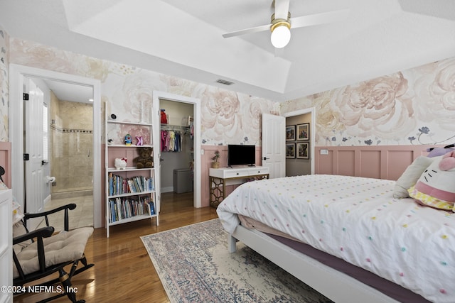 bedroom featuring dark wood-type flooring, ensuite bathroom, a walk in closet, ceiling fan, and a closet