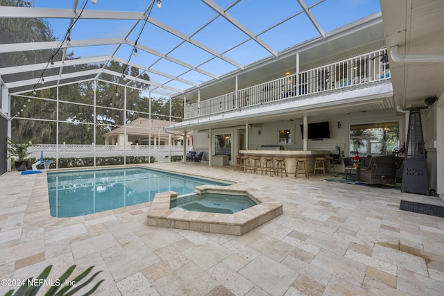 view of pool with a lanai, an in ground hot tub, exterior bar, and a patio