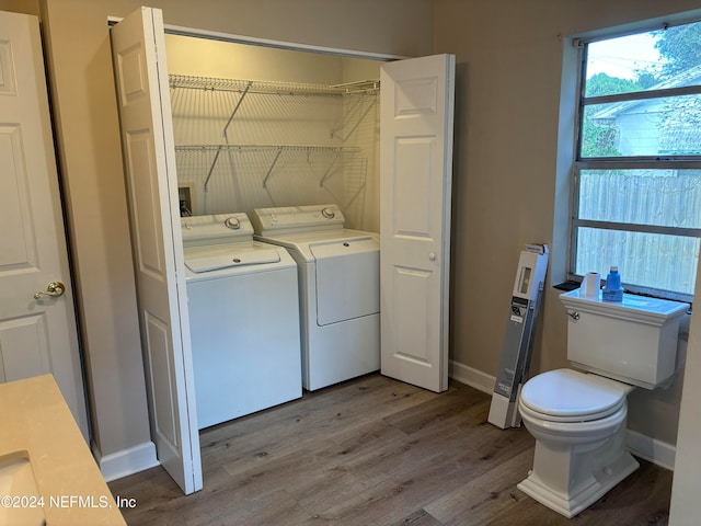 clothes washing area with washing machine and clothes dryer and light hardwood / wood-style flooring