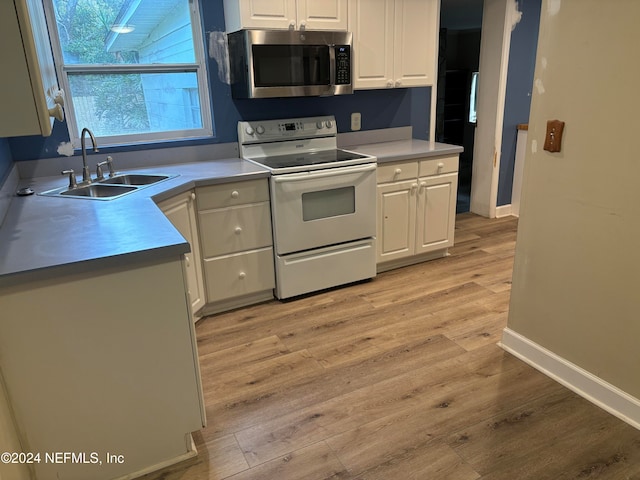 kitchen with white range with electric cooktop, light wood-type flooring, white cabinetry, and sink