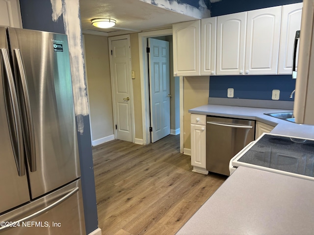 kitchen featuring appliances with stainless steel finishes, light wood-type flooring, and white cabinetry