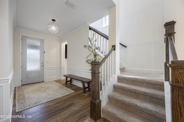 entryway featuring dark hardwood / wood-style flooring, crown molding, and an inviting chandelier