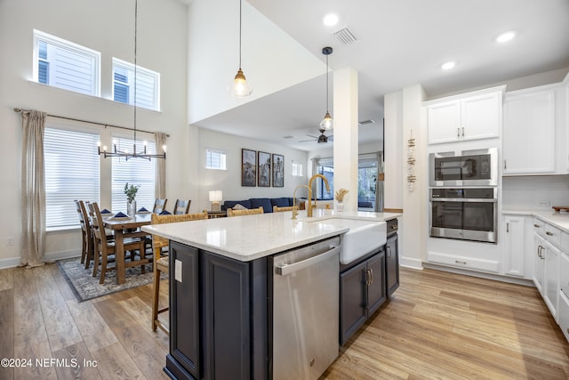 kitchen with sink, light hardwood / wood-style flooring, white cabinets, ceiling fan with notable chandelier, and appliances with stainless steel finishes