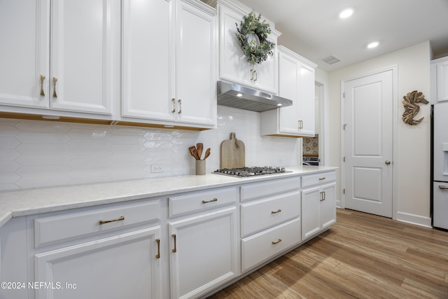 kitchen with tasteful backsplash, white cabinetry, light hardwood / wood-style floors, and stainless steel gas cooktop