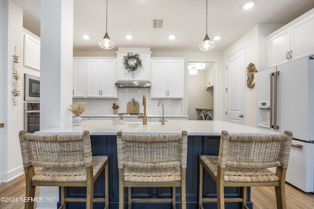 kitchen with decorative light fixtures, light wood-type flooring, appliances with stainless steel finishes, and tasteful backsplash