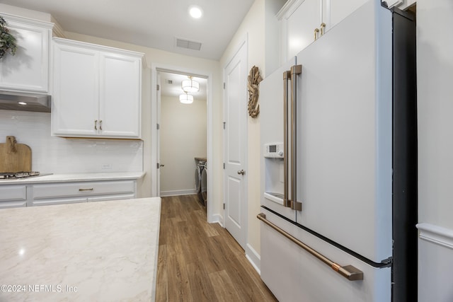 kitchen featuring dark wood-type flooring, white cabinets, decorative backsplash, range hood, and high end white refrigerator