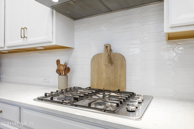 room details with decorative backsplash, white cabinetry, and stainless steel gas cooktop