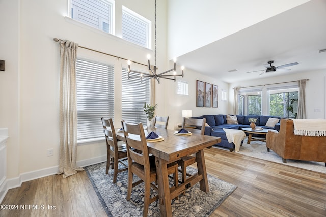 dining space with ceiling fan with notable chandelier and light wood-type flooring