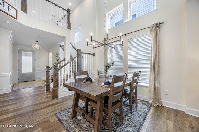 dining space with plenty of natural light, ornamental molding, dark wood-type flooring, and a high ceiling