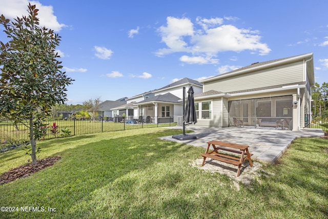 rear view of property featuring a sunroom, a patio area, and a yard