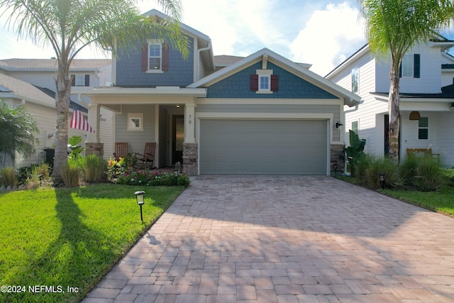 craftsman-style home featuring covered porch, a front yard, and a garage