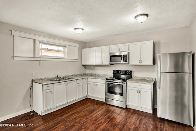 kitchen featuring appliances with stainless steel finishes, white cabinetry, dark wood-type flooring, and sink