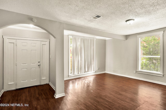 foyer entrance with a textured ceiling, dark hardwood / wood-style floors, and ornamental molding