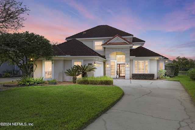 front facade featuring french doors, a garage, and a lawn