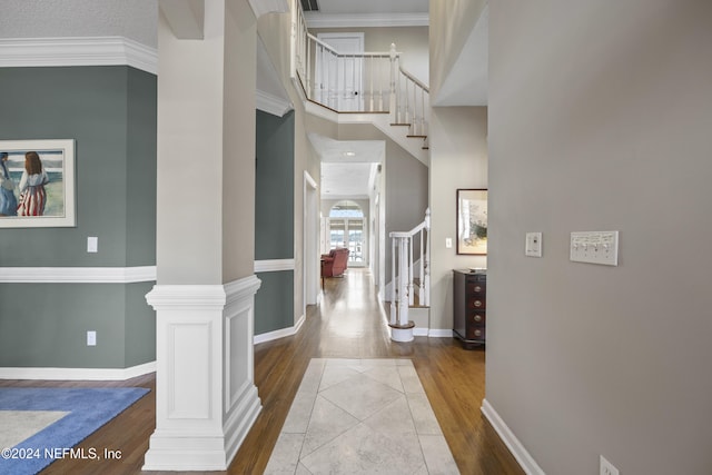 foyer entrance with hardwood / wood-style floors, decorative columns, ornamental molding, and a high ceiling