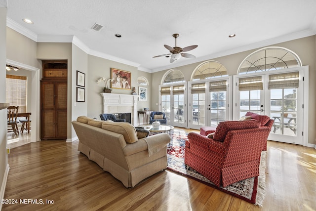 living room with ceiling fan, wood-type flooring, crown molding, and french doors