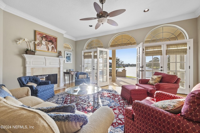 living room with french doors, ceiling fan, ornamental molding, light wood-type flooring, and a fireplace