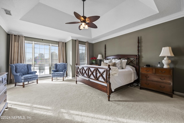 carpeted bedroom featuring a tray ceiling, ceiling fan, and crown molding