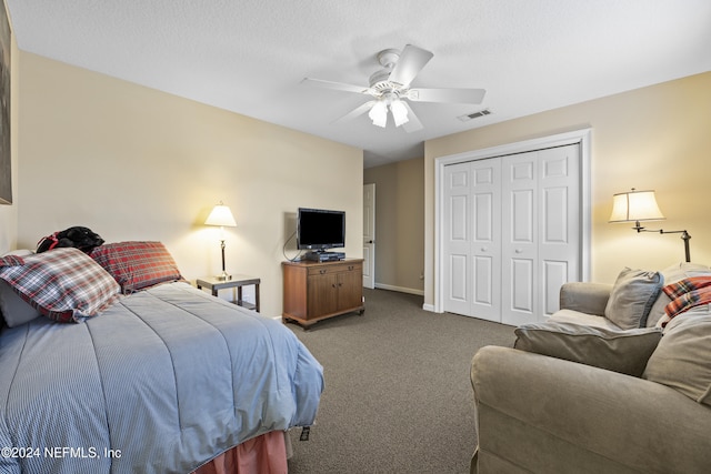 bedroom with ceiling fan, a closet, a textured ceiling, and dark colored carpet